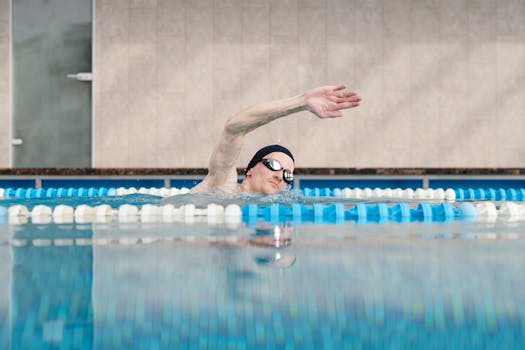 A male swimmer trains in an indoor pool, showcasing the freestyle stroke technique.