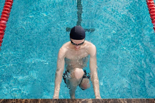 Мужчина в черных шортах плавает в бассейне