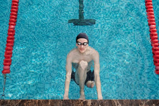 Adult man swimming in a pool with goggles, focused on fitness and health.