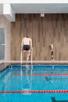 Man with prosthetic leg entering swimming pool, showcasing determination and fitness.