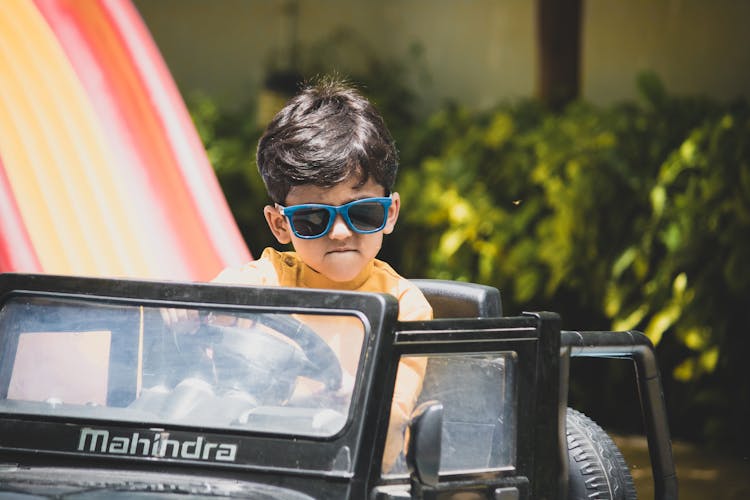 Photograph Of A Child Driving A Toy Car