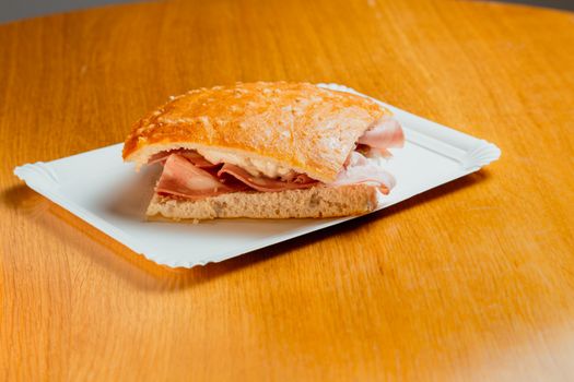 Tasty prosciutto sandwich served on a paper plate, perfect for a quick and satisfying meal.