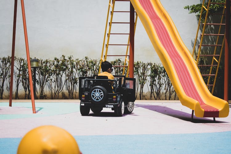 Photo Of A Kid Driving A Toy Car At The Playground