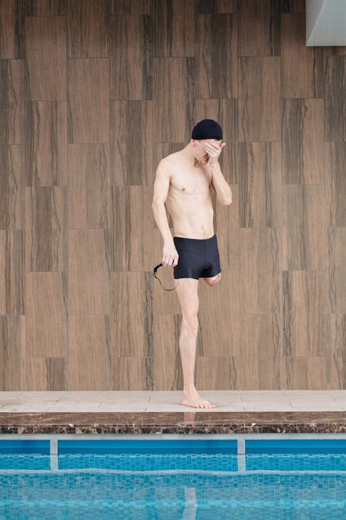 Photo Of Topless Man Standing Beside Pool 