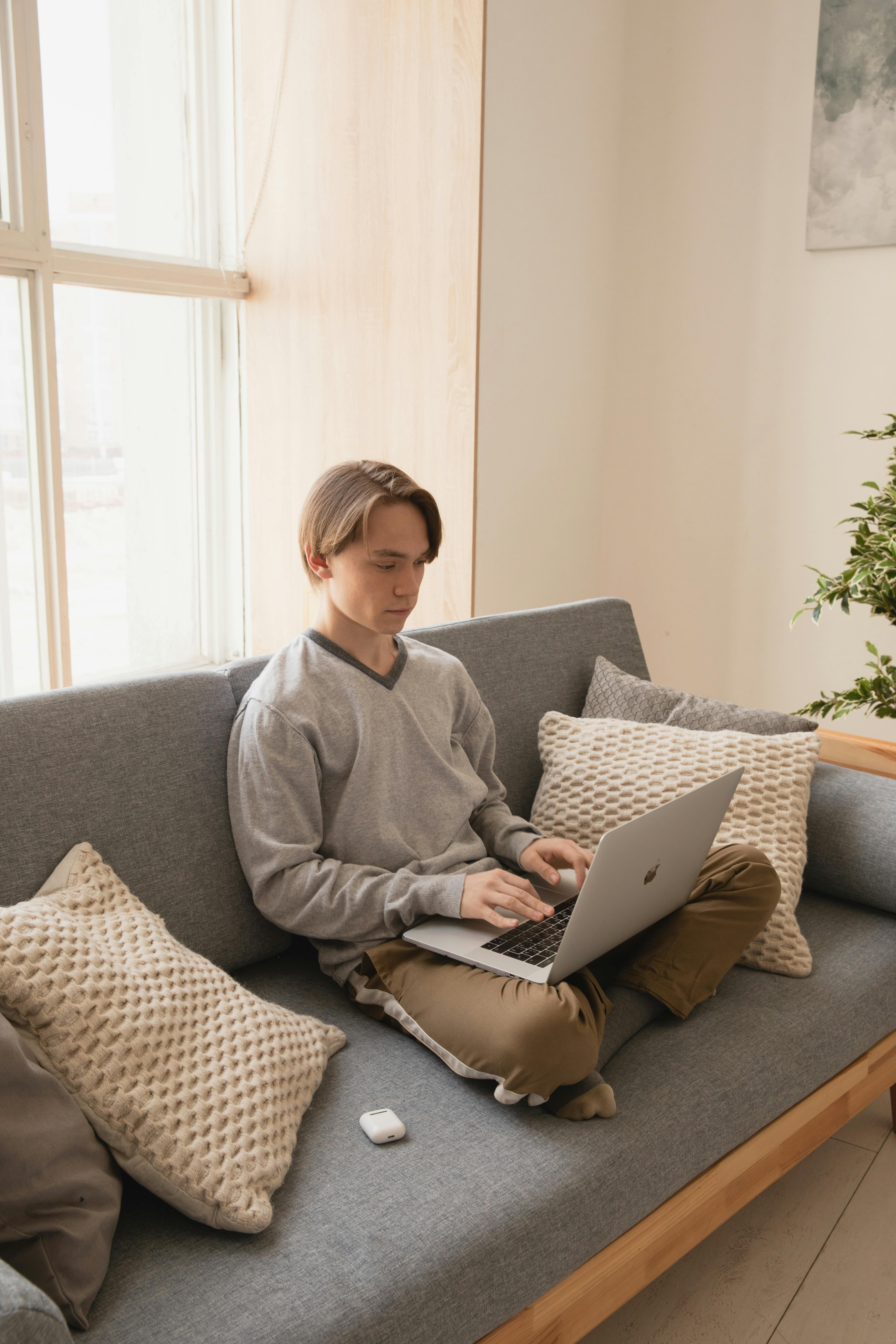 remote employee typing on laptop while sitting on sofa