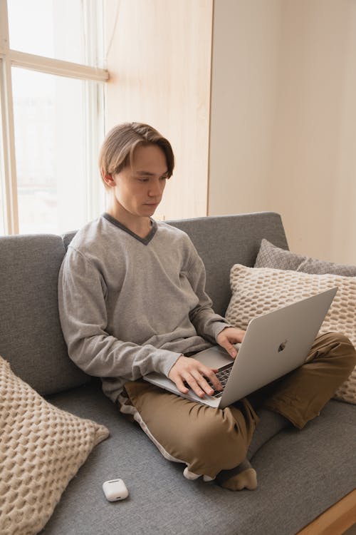 Free Thoughtful male freelancer working on laptop at home in daylight Stock Photo