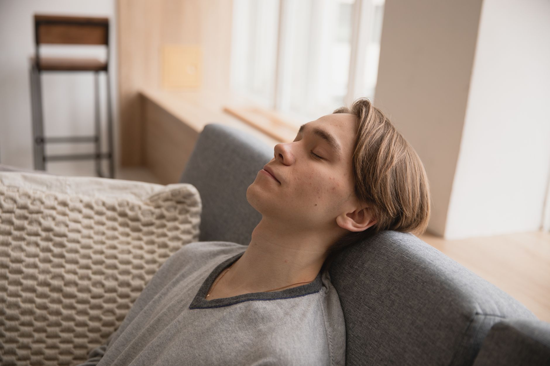 Young man relaxing on a comfortable sofa at home, enjoying a peaceful moment indoors.