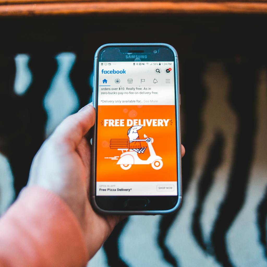 Smartphone showing a Facebook ad for free pizza delivery; a Facebook ads for beginners example.