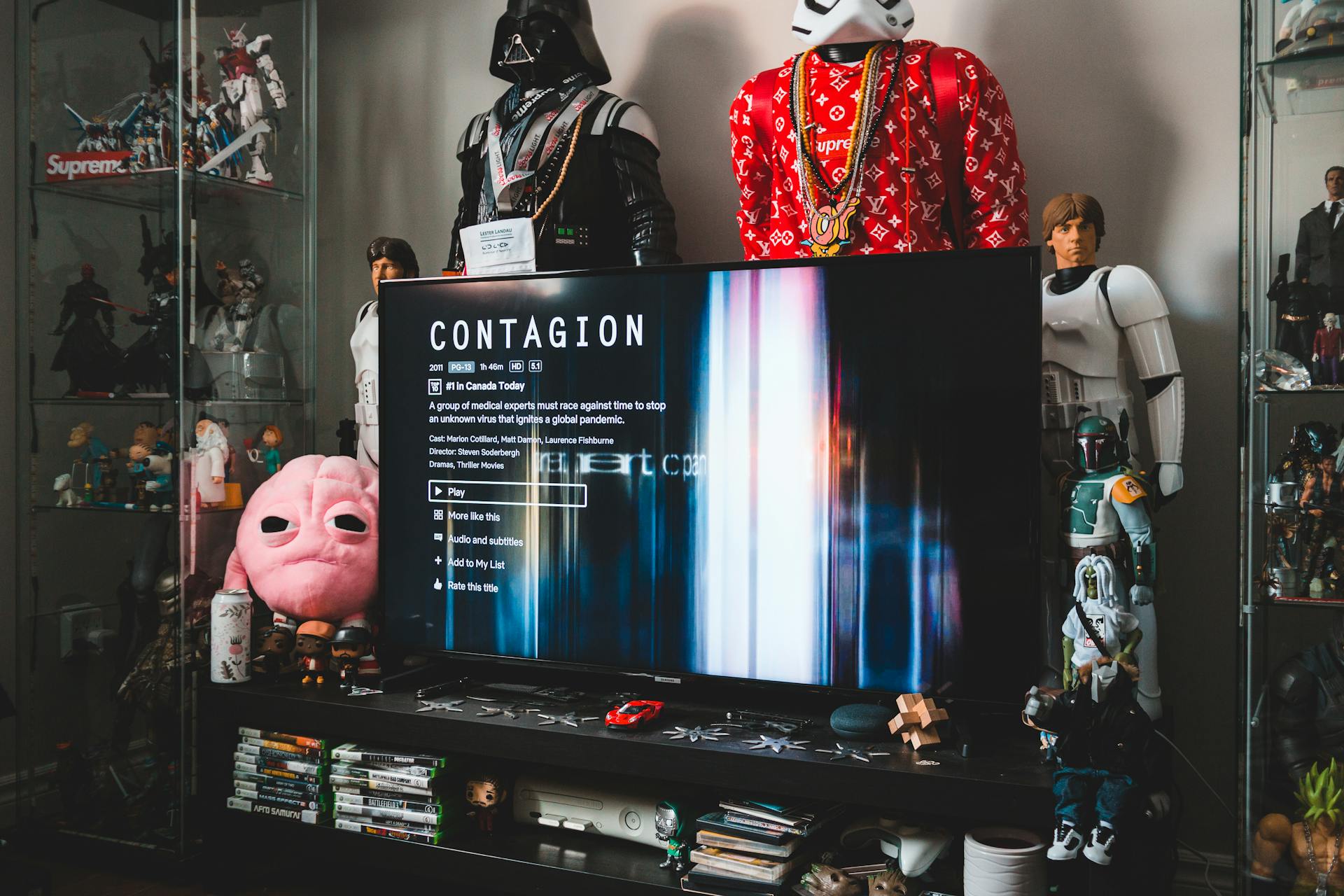 Desktop computer with creative video game on screen near assorted toy superheros on glass shelves in modern style apartment