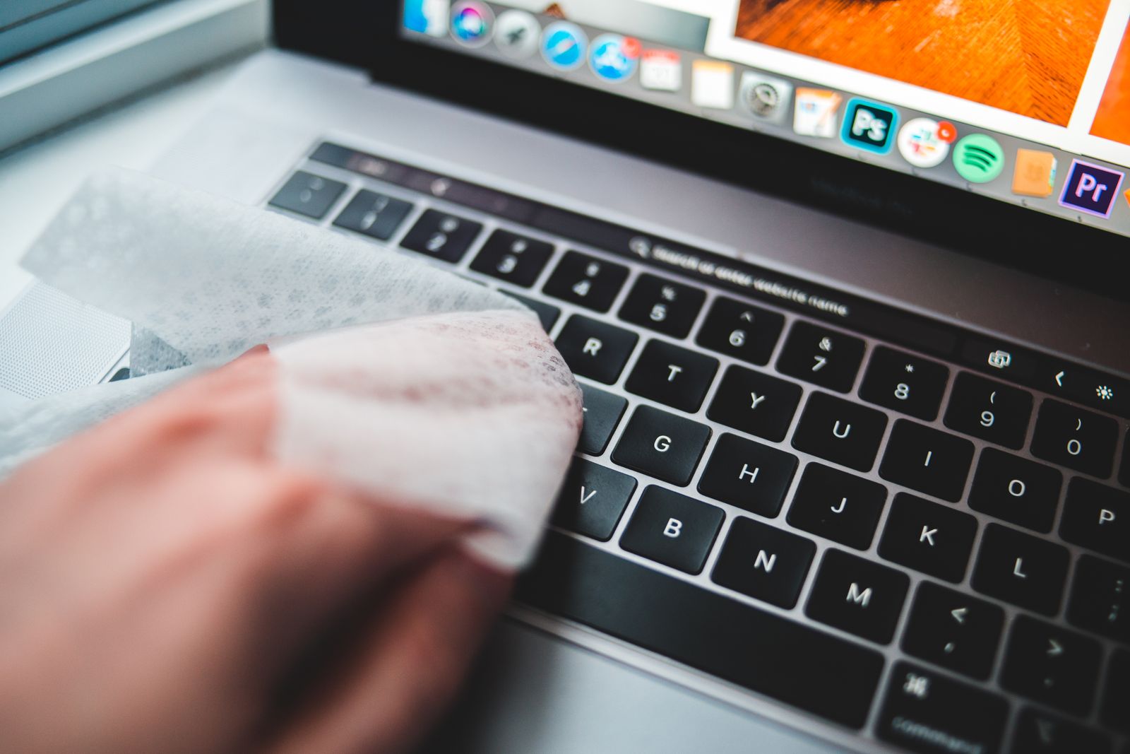 Person carefully cleaning a computer keyboard with a soft wipe