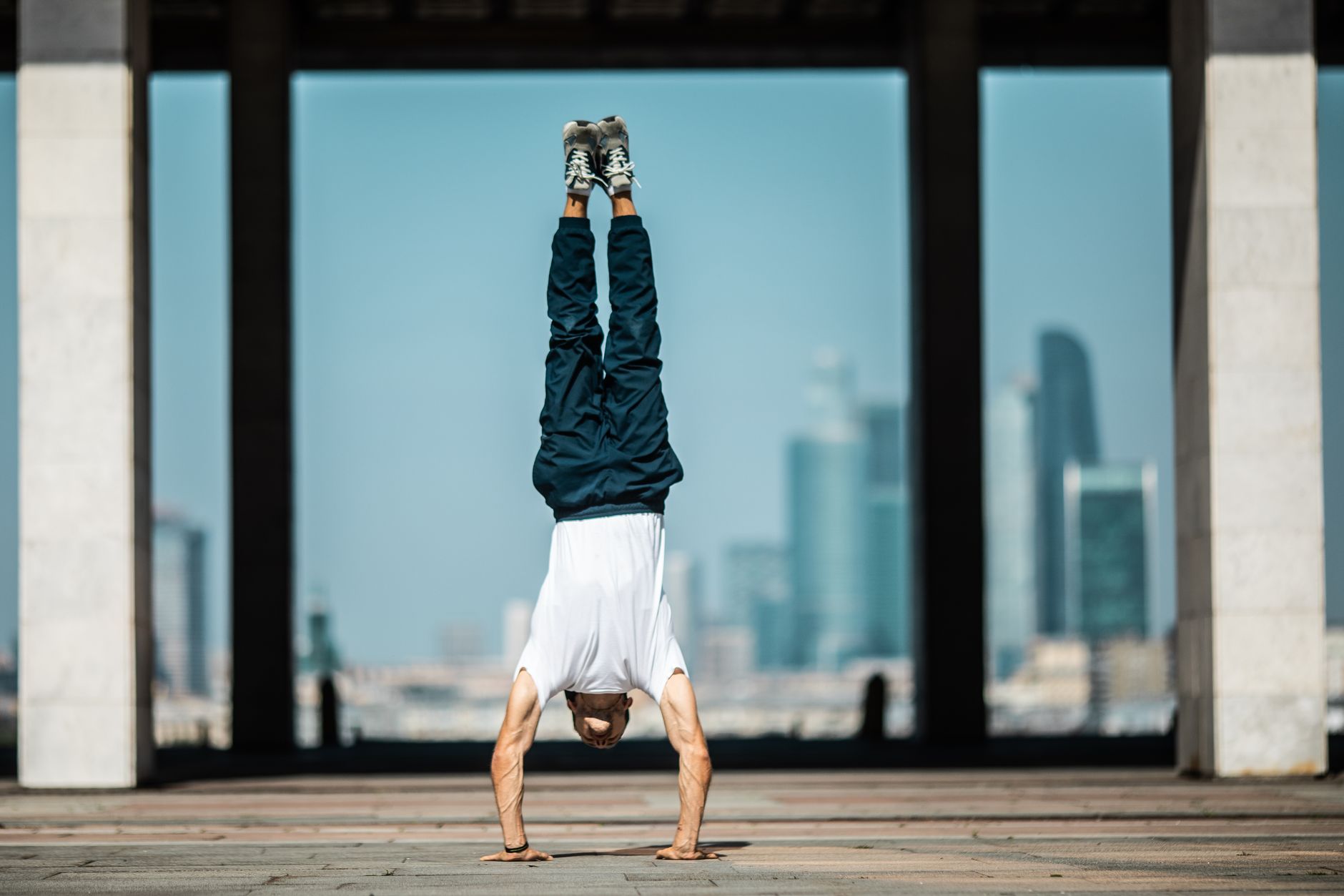 Man performing a handstand outdoors with a cityscape backdrop, embodying strength and balance.