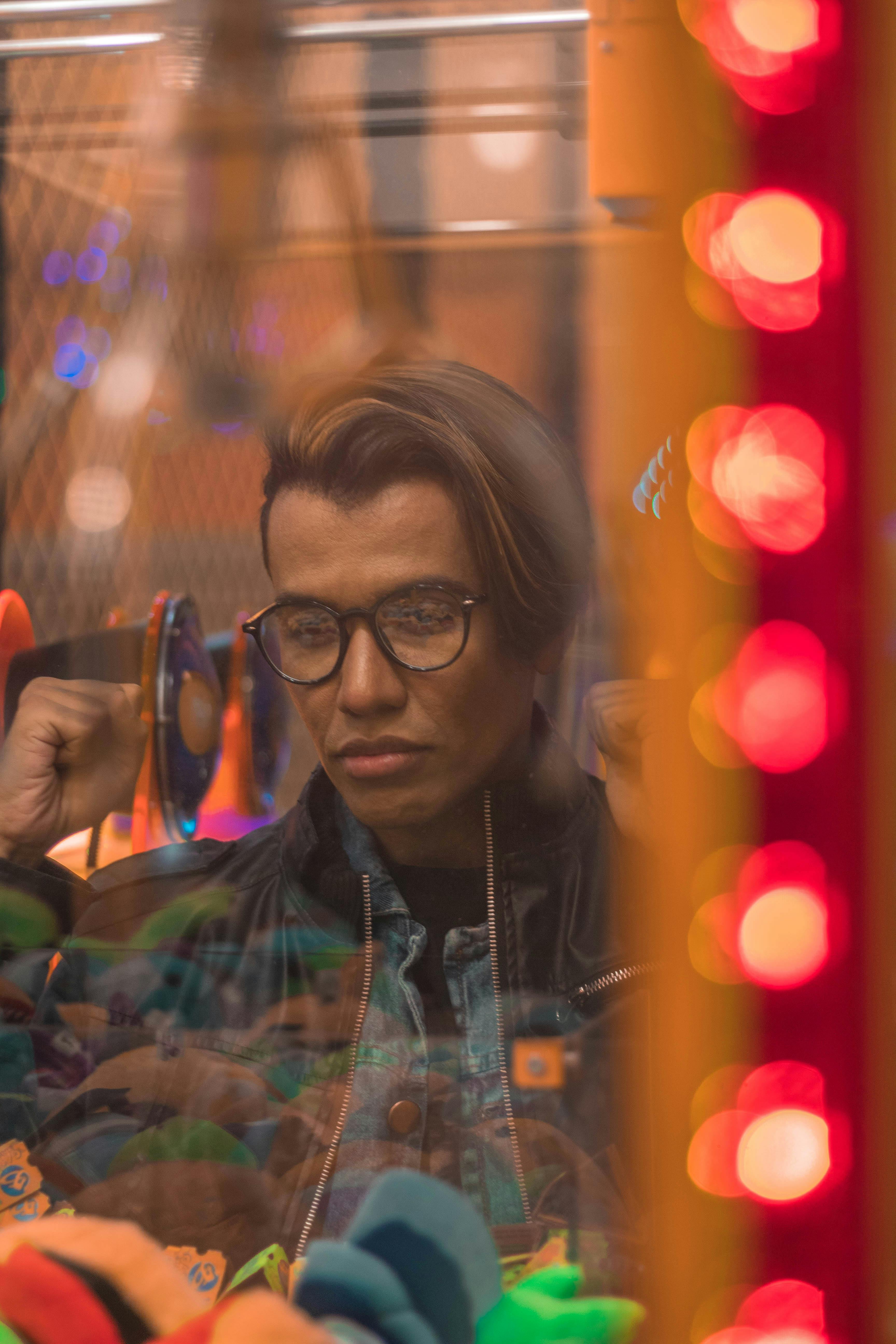 一名男子若有所思地透过玻璃看着，周围是充满活力的散景灯光