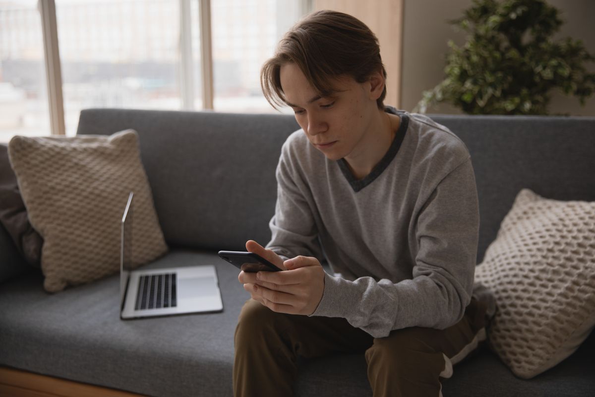 Koltukta oturan kişi elinde akıllı telefon tutuyor, maç takibi yapıyor