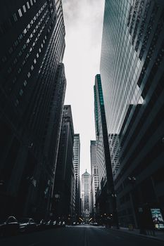 从低角度仰望，芝加哥摩天大楼排列在城市街道上空，映衬着多云的天空