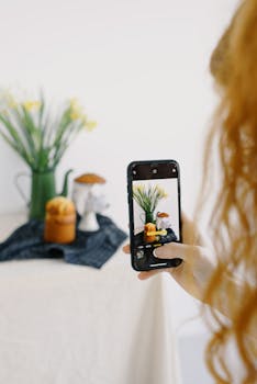 A person photographing a still life composition with a smartphone camera.