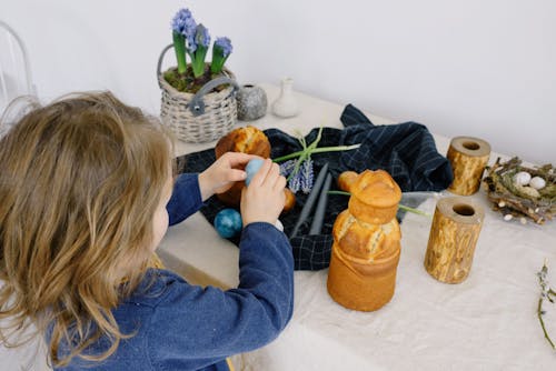 Little Girl Holding an Egg over a Table With Easter Decorations