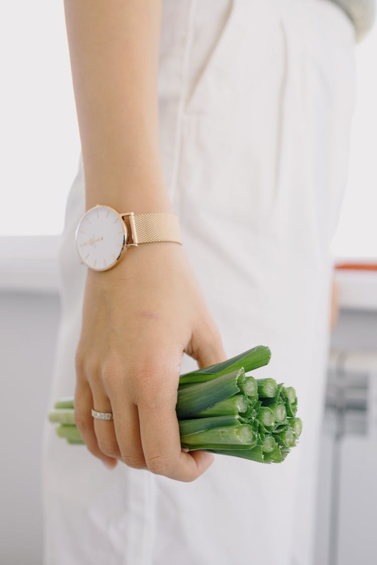 Crop Person Holding Fresh Green Onions In Light Kitchen At Home