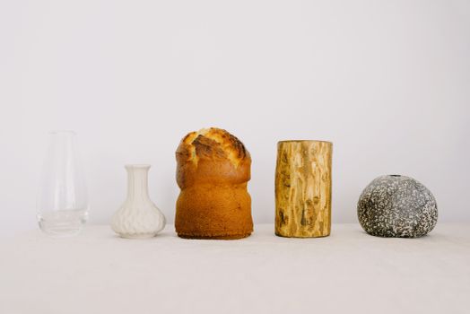 Traditional Easter cake with wood chock and various vases placed on white table against white wall as symbol of traditional Easter holiday