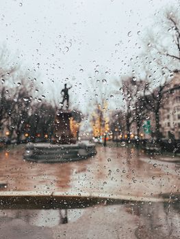 窗上的雨点模糊了城市雕塑和灯光，营造出一种忧郁的氛围