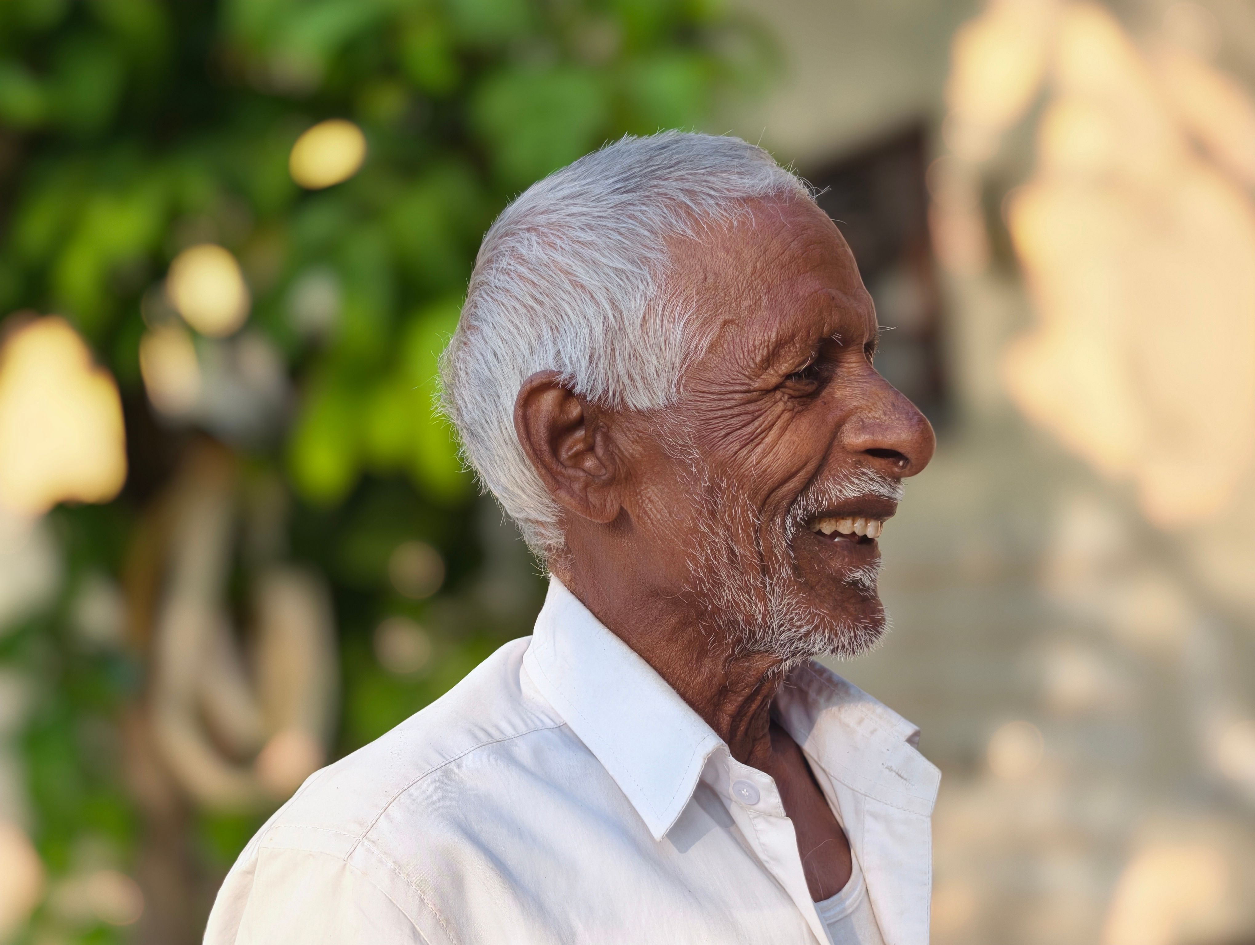 Elderly Man Smiling Outdoors in Sunlight · Free Stock Photo