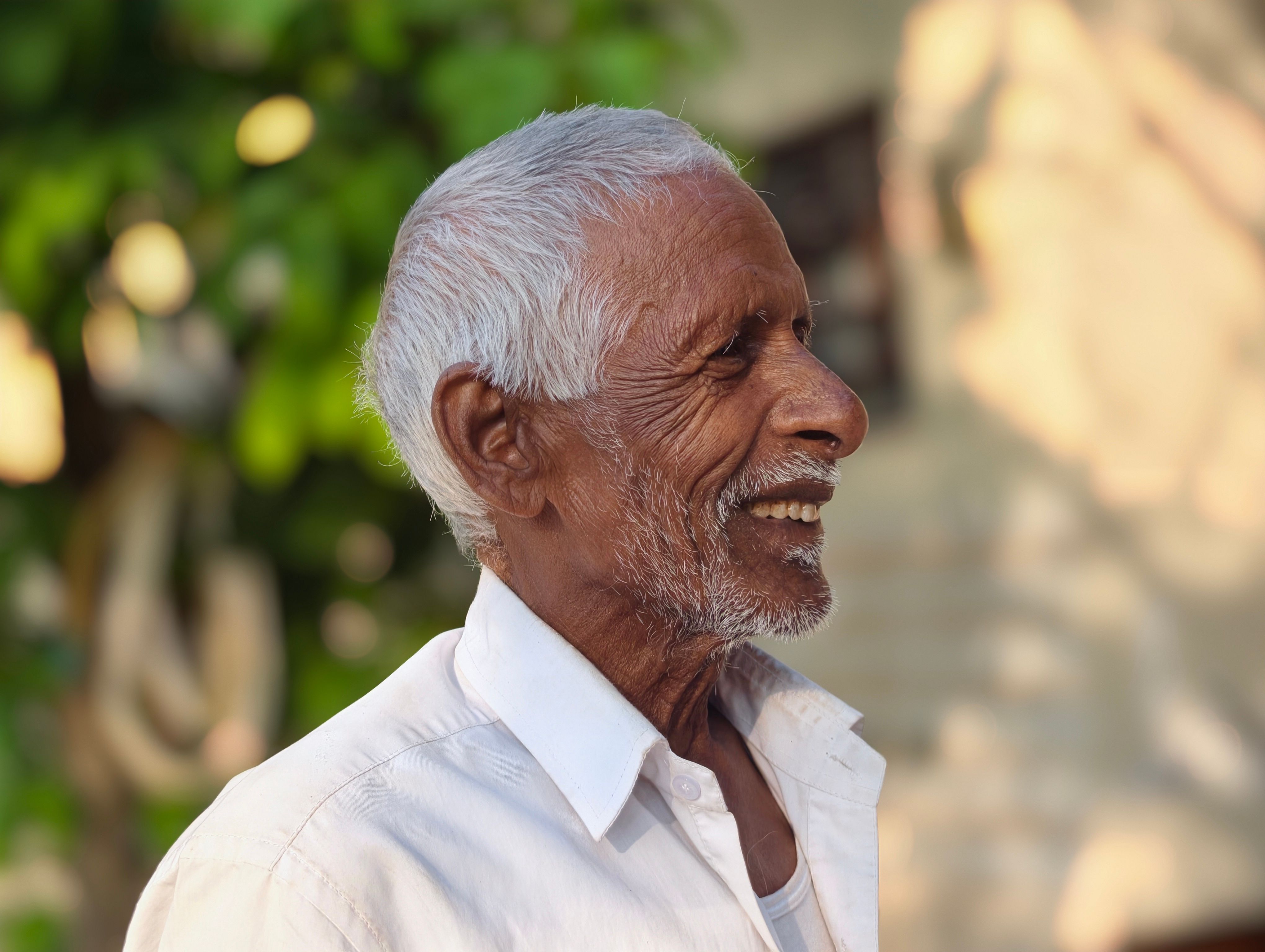 Elderly Man Smiling Outdoors in Sunlight · Free Stock Photo
