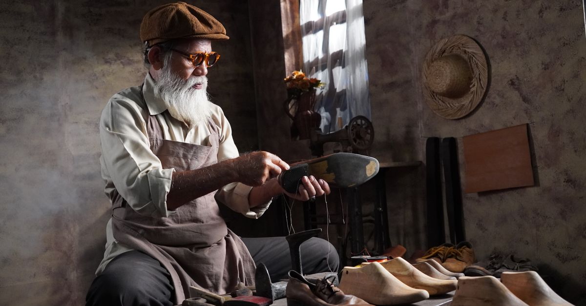 Elderly cobbler handcrafting leather shoes in a vintage workshop setting.