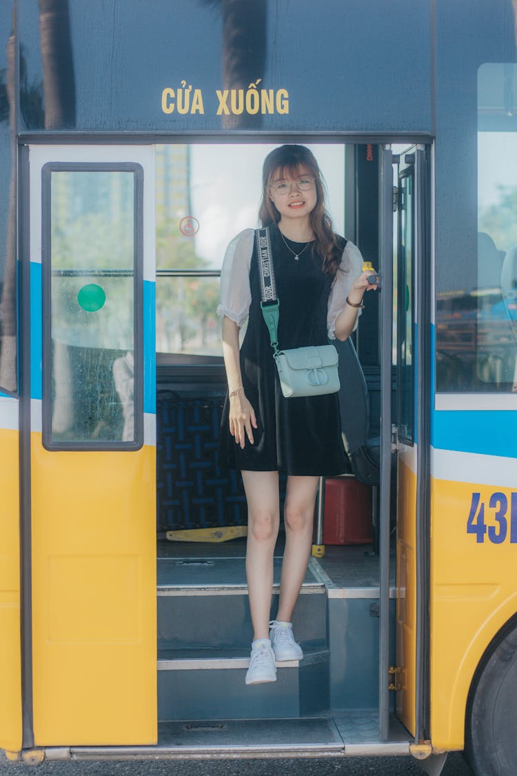 Content Female Asian Passenger Getting Off Colorful Bus In Town