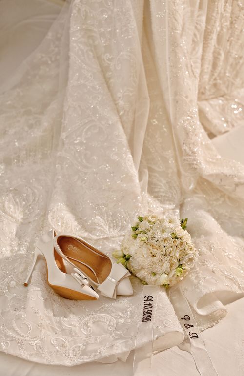 Free White bridal heels and bouquet on an elegant wedding dress, highlighting classic wedding style. Stock Photo