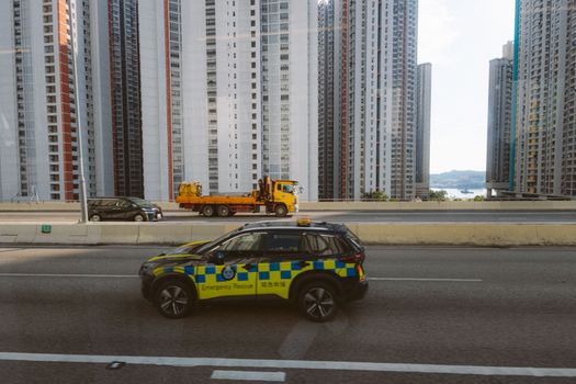 Cityscape featuring high-rise buildings and an emergency vehicle on the highway.