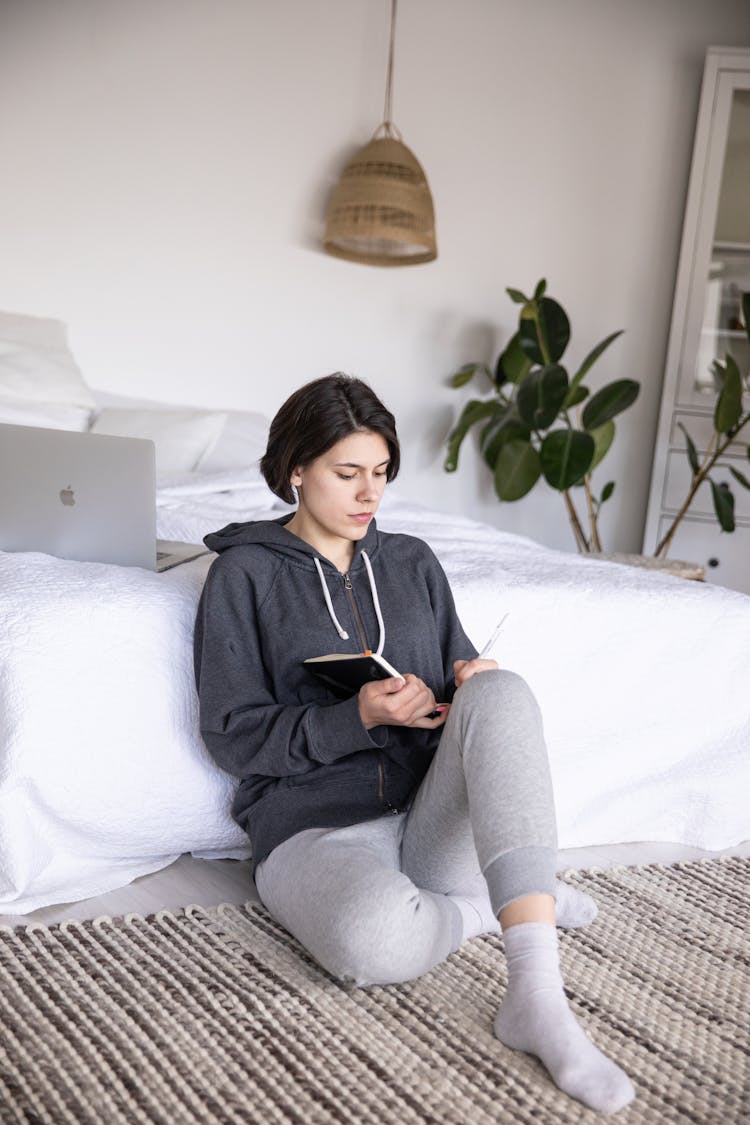 Relaxed Young Woman Reading Book On Floor At Home