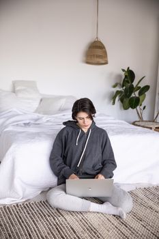 一位女士在装饰时尚、舒适现代的卧室里用笔记本电脑工作