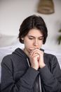 一名年轻女子穿着连帽衫，坐在舒适的房间里若有所思