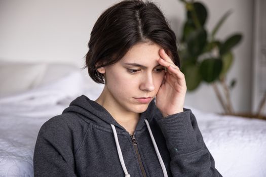 照片在室内拍摄，一位穿着连帽衫的年轻女子看起来若有所思