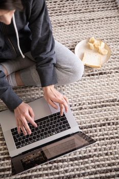 Casual work-from-home scene with a laptop and snack on a cozy carpet. Ideal for lifestyle themes.
