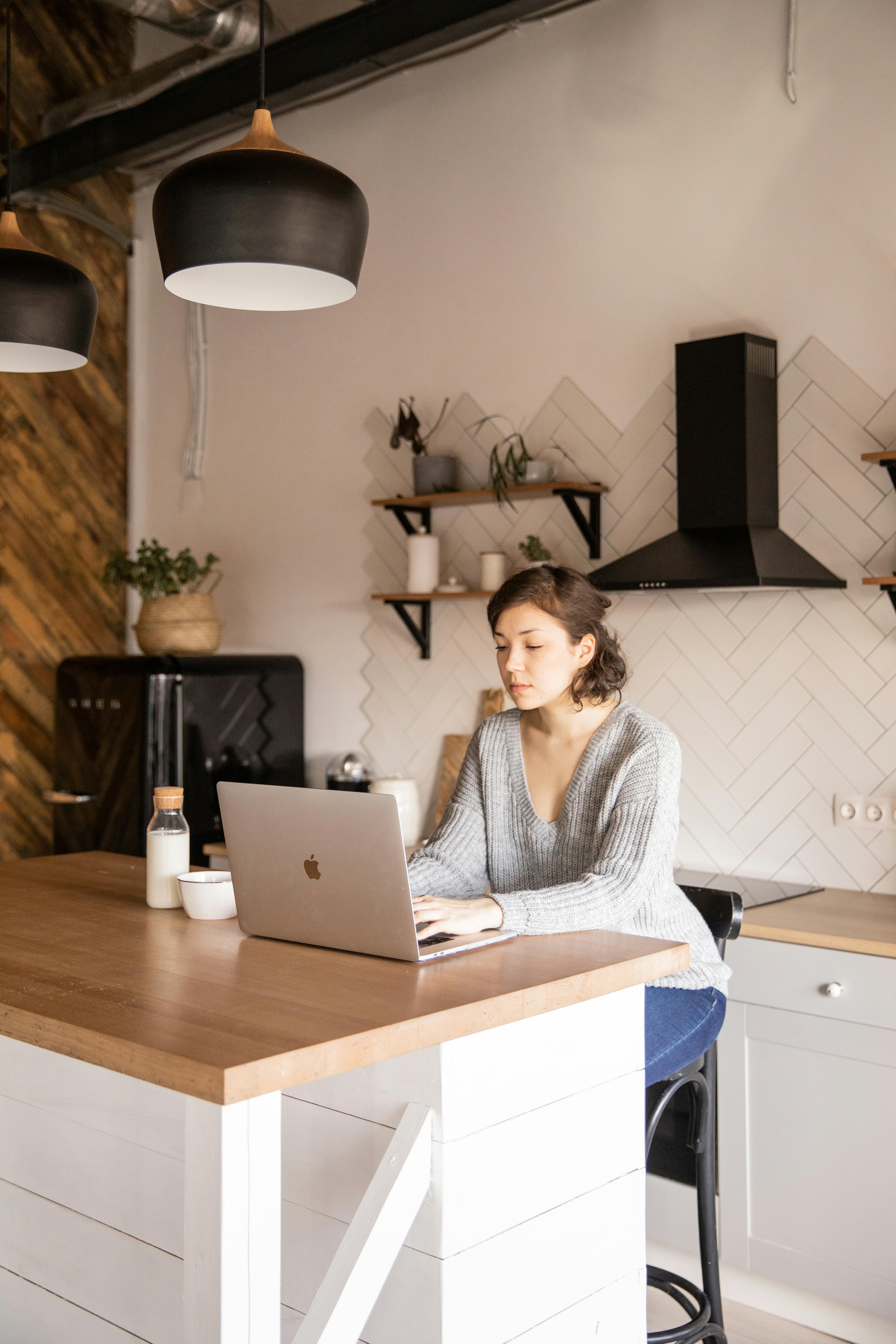 young female freelancer using laptop in kitchen