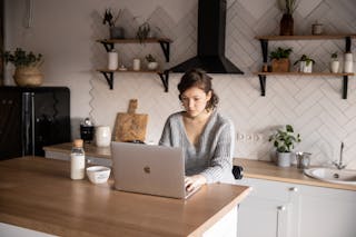 Content young woman browsing laptop in modern kitchen