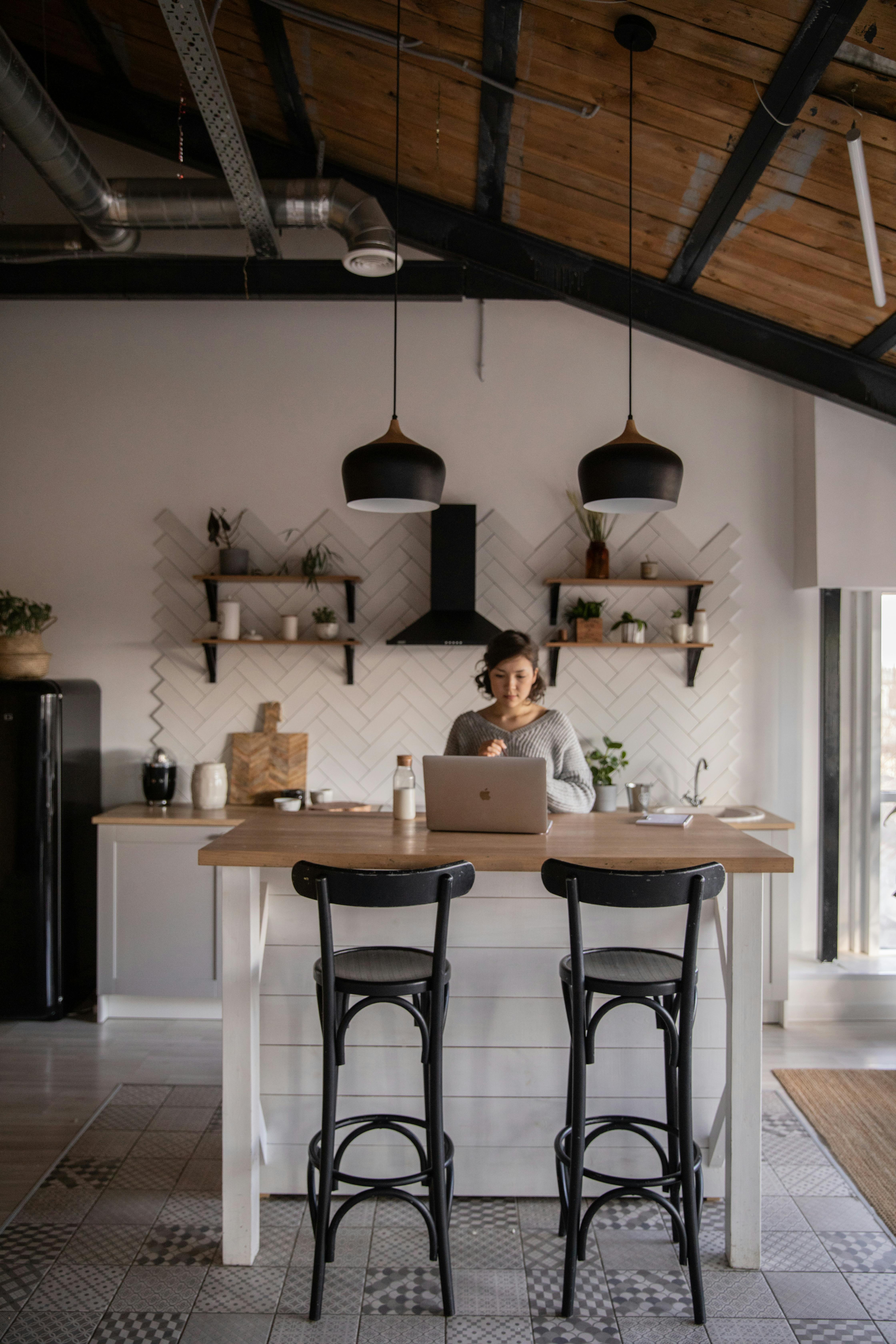 young woman with laptop in modern kitchen interior