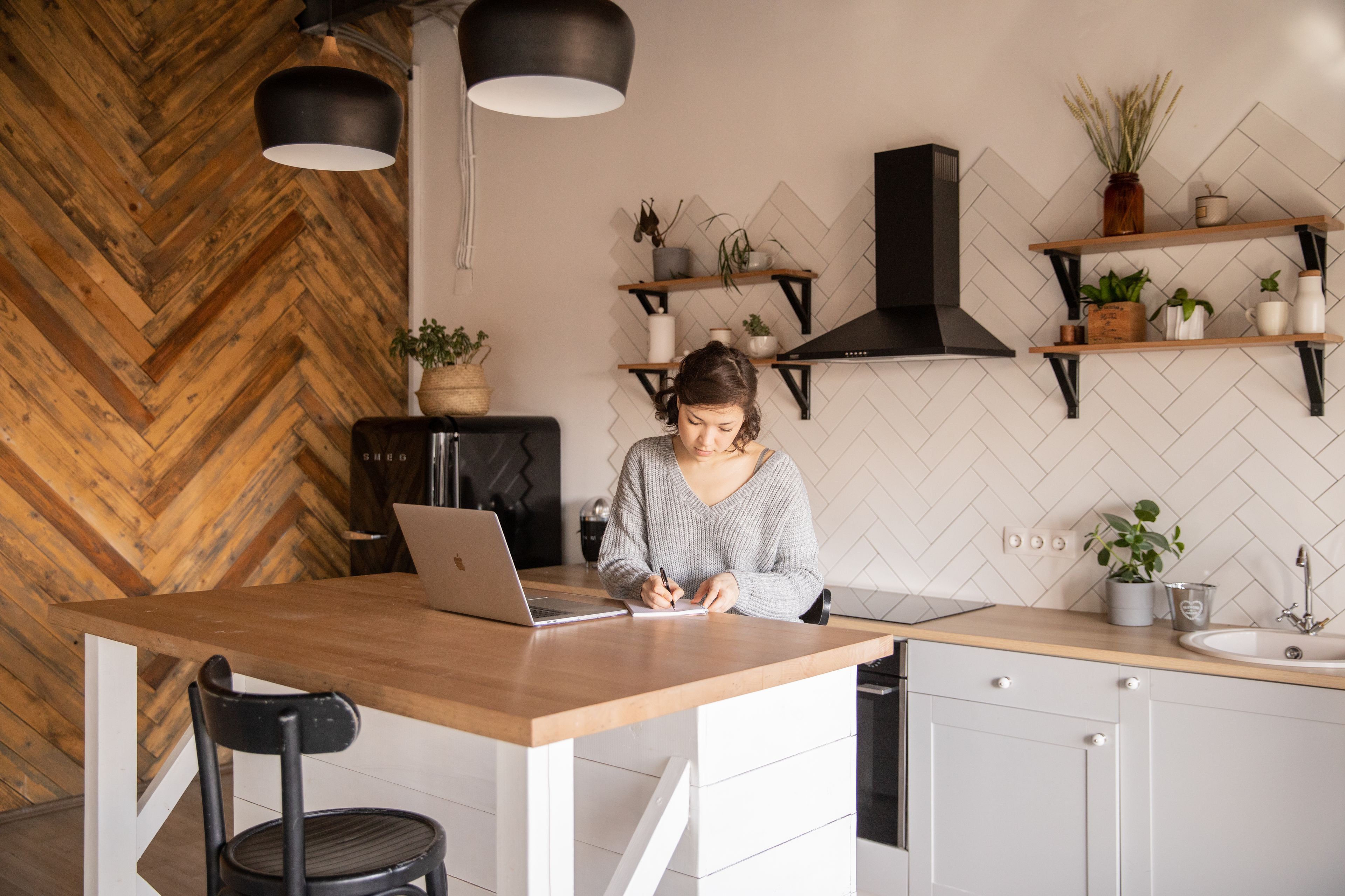 A business owner drafting notes beside her laptop