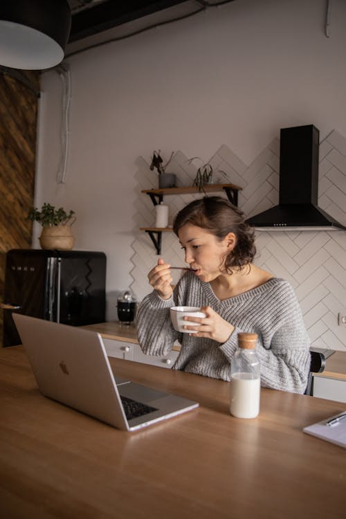 Young woman using laptop during breakfast