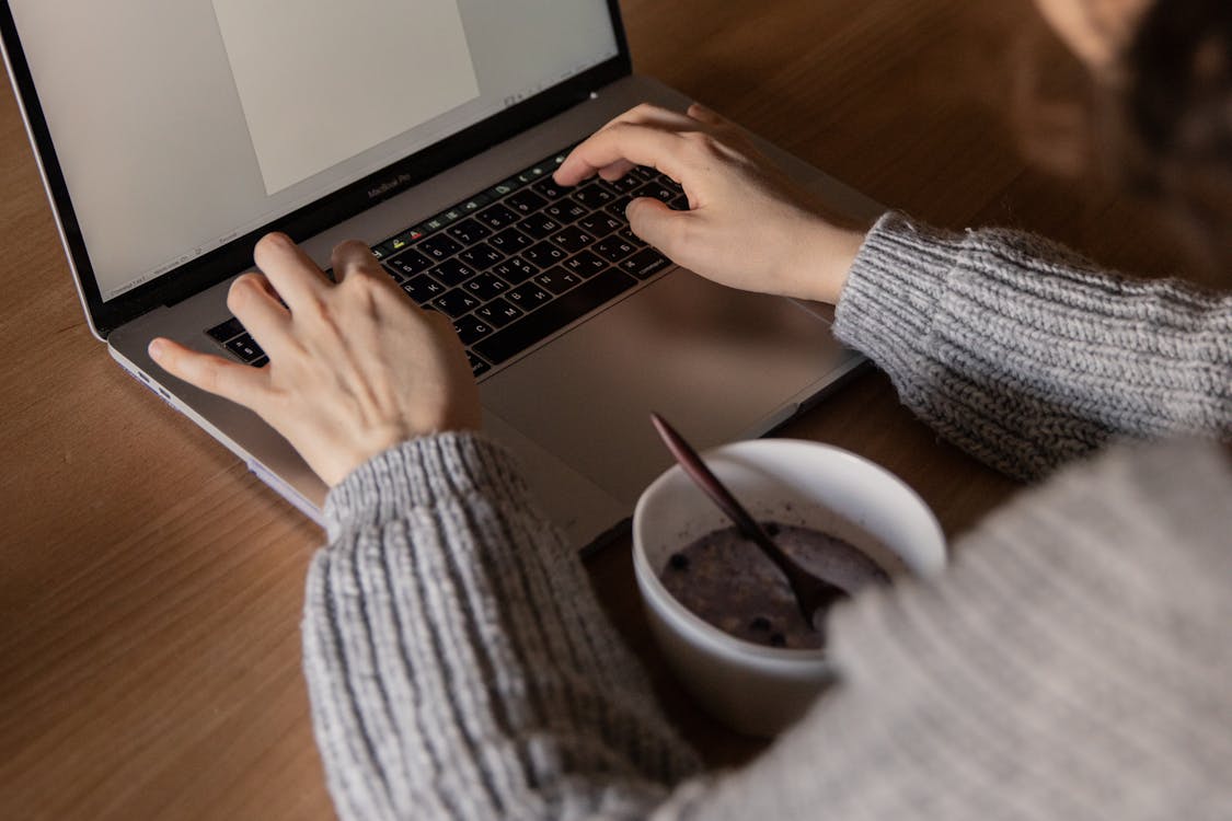 Crop businesswoman using laptop during meal