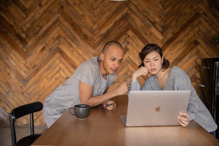 Focused Couple Using Laptop In Kitchen