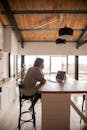 一名妇女在厨房柜台上用笔记本电脑工作，这间现代公寓装有木天花板