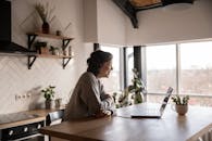 Happy woman video chatting on laptop in kitchen