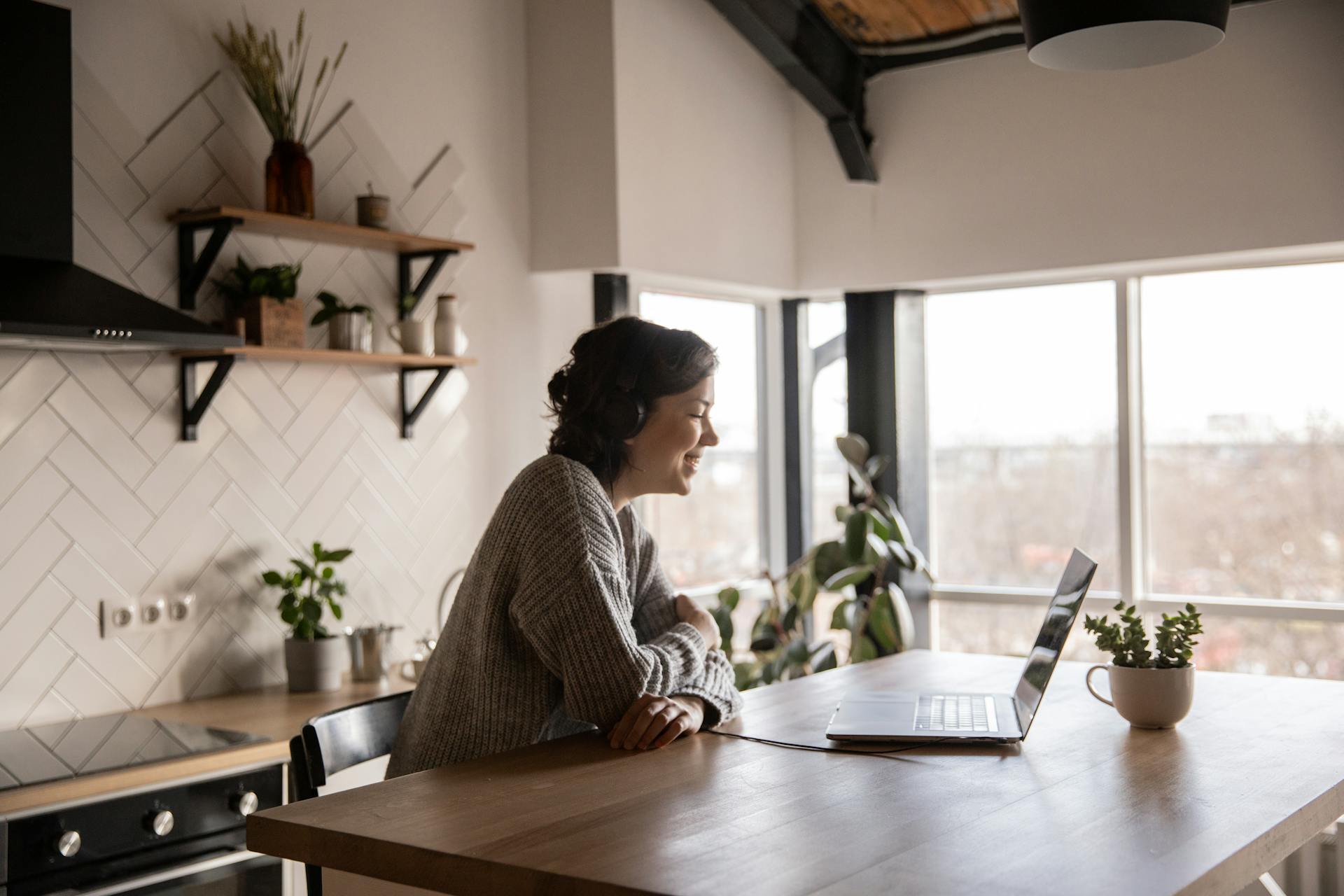 Happy woman video chatting on laptop in kitchen