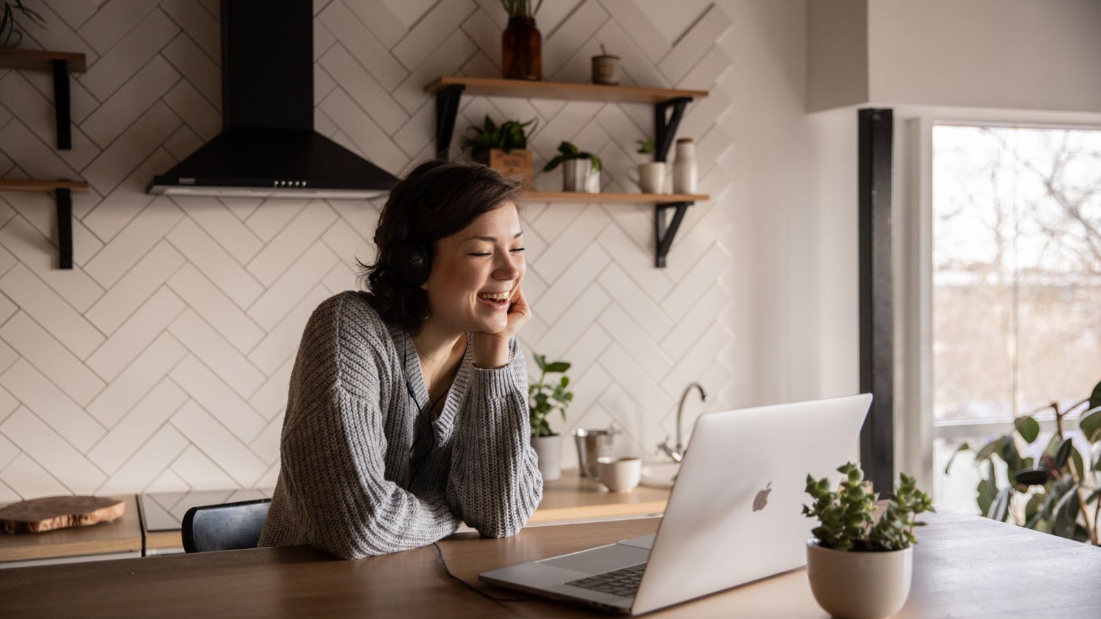 Mom working at a kitchen-counter home office with a laptop and a mug