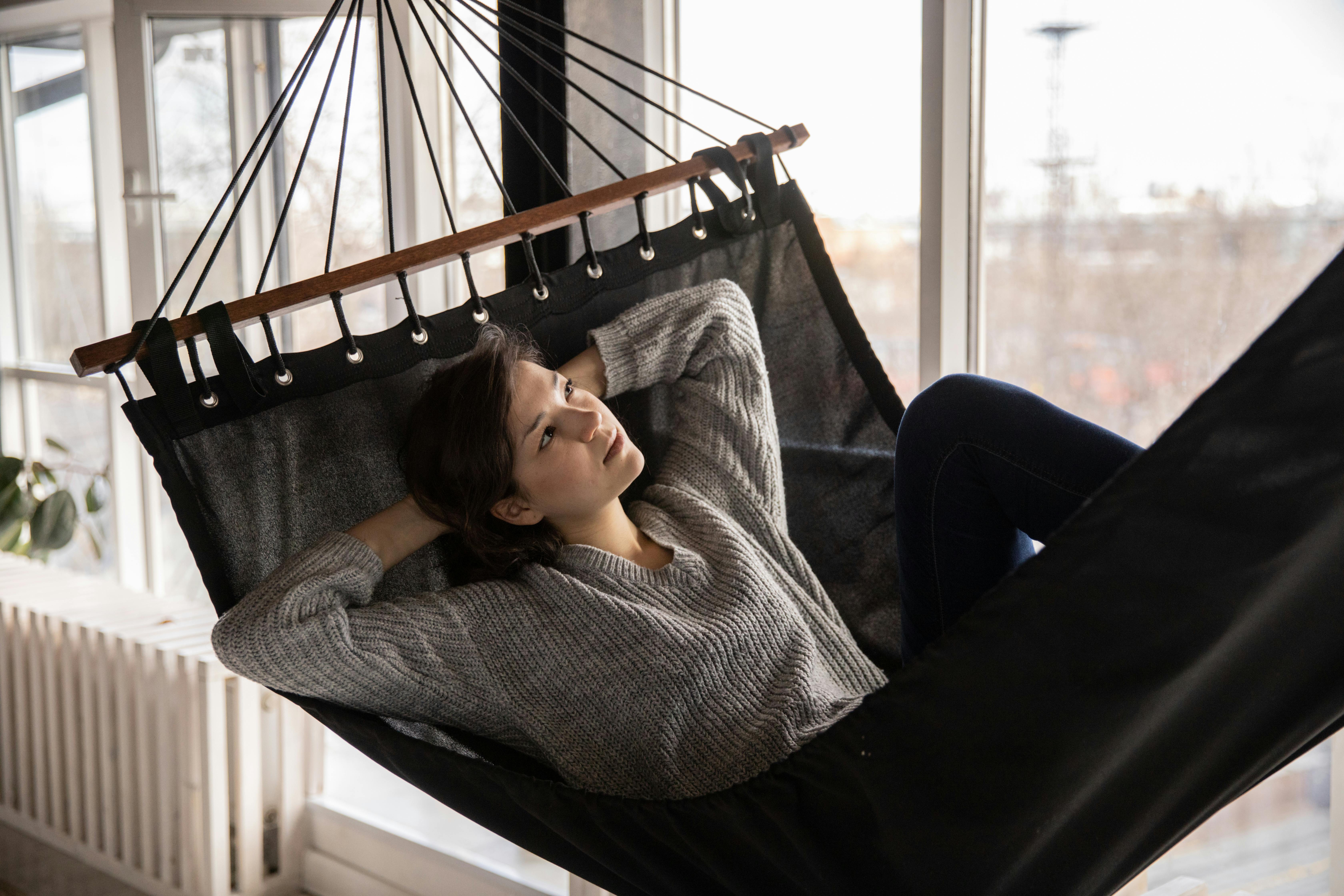 pensive woman relaxing in stylish hammock