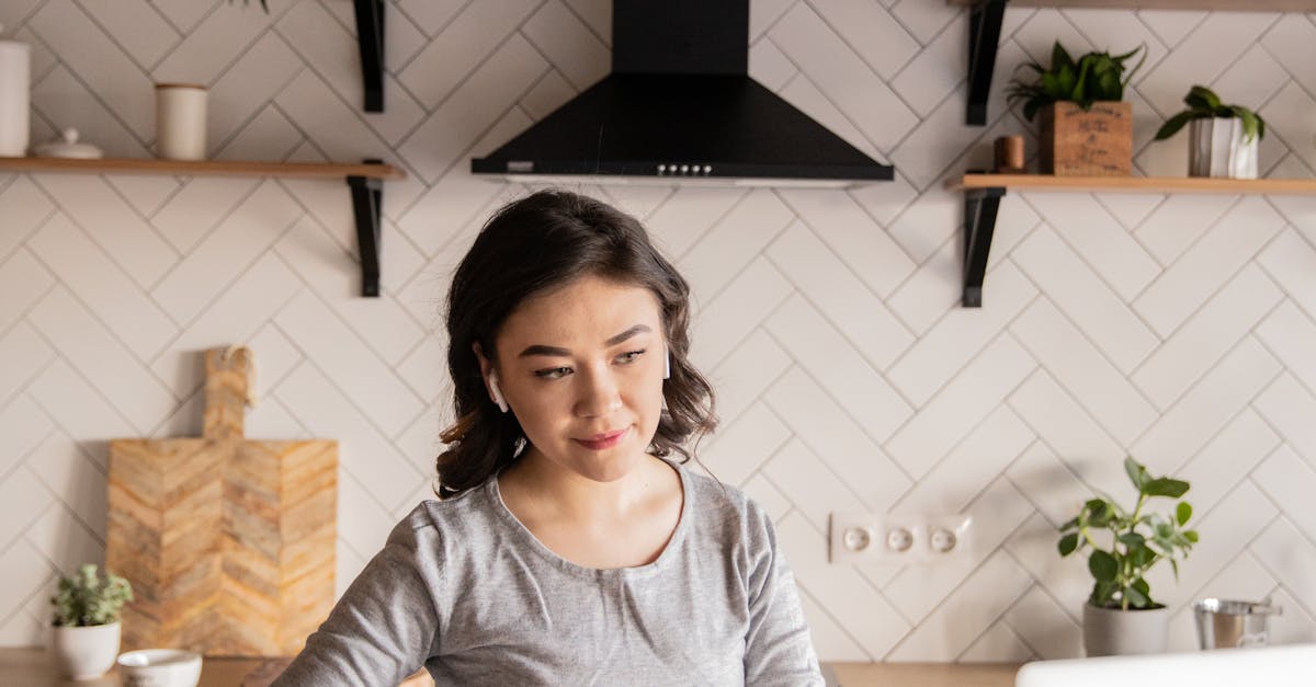 Young woman cooking while watching video on laptop