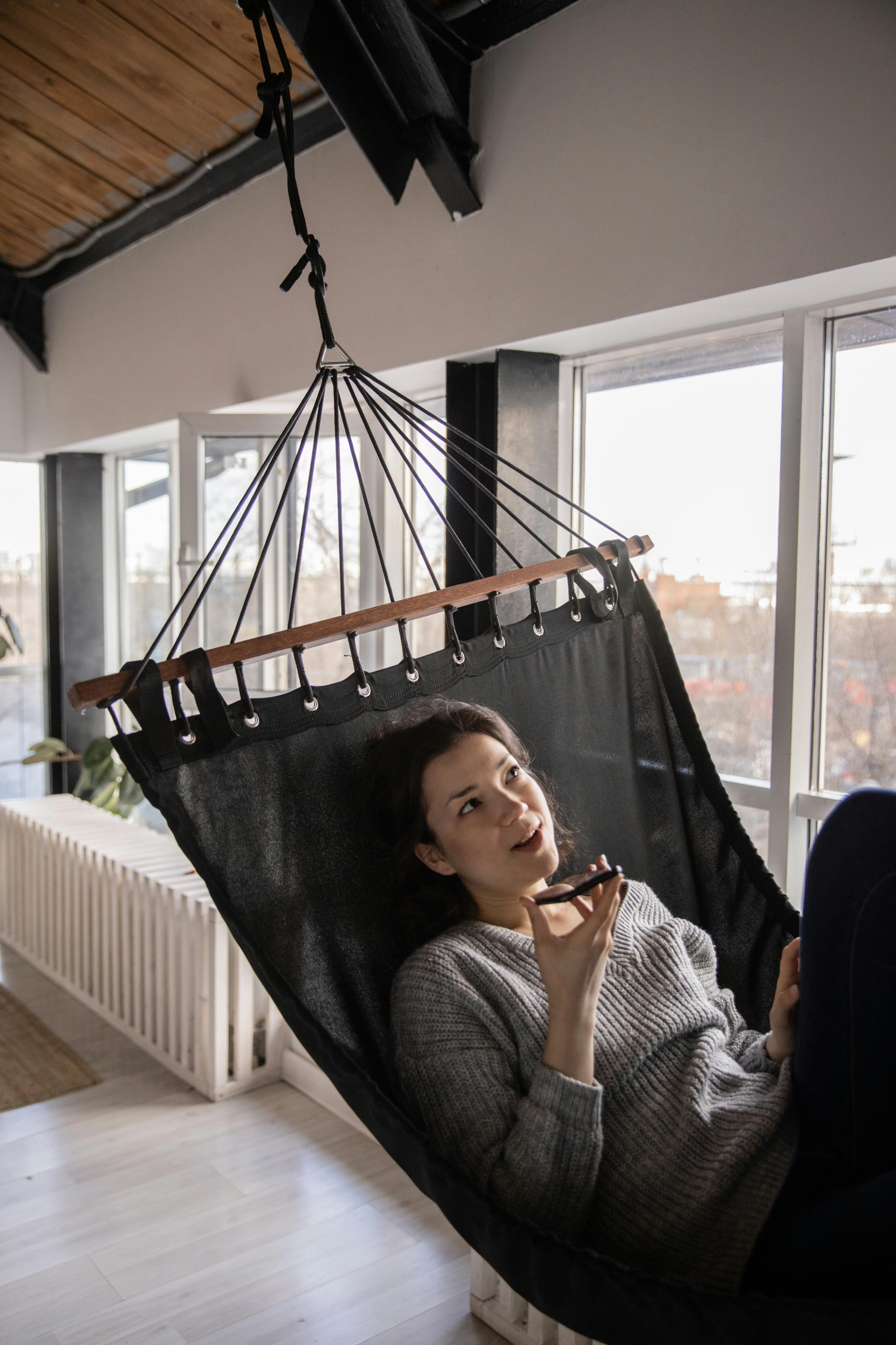 dreamy woman talking on smartphone while lying in hammock