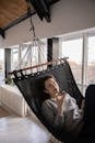 Dreamy woman talking on smartphone while lying in hammock