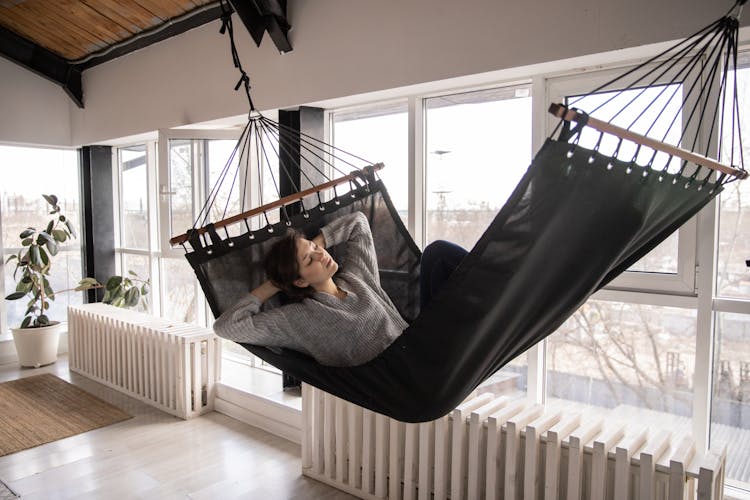 Young Woman Resting In Hammock At Home In Daylight